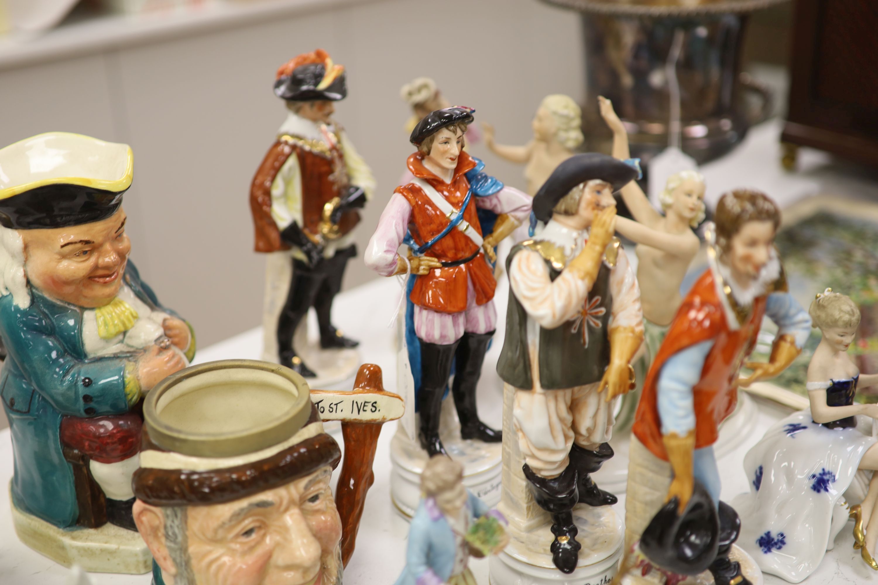 A group of porcelain figurines and two Toby jugs